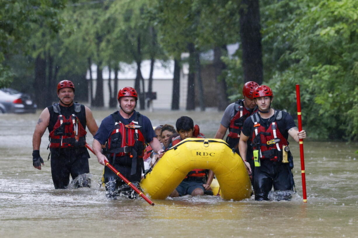 FILE - Members of the Balch Springs Fire Department bring a family of four by boat to higher ground after rescuing them from their home along Forest Glen Lane in Batch Springs, Texas, Aug. 22, 2022. This summer the weather has not only been extreme, but it has whiplashed from one extreme to another. Dallas, St. Louis, Kentucky, Yellowstone, Death Valley all lurched from drought to flood.