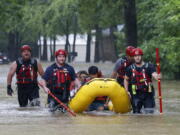 FILE - Members of the Balch Springs Fire Department bring a family of four by boat to higher ground after rescuing them from their home along Forest Glen Lane in Batch Springs, Texas, Aug. 22, 2022. This summer the weather has not only been extreme, but it has whiplashed from one extreme to another. Dallas, St. Louis, Kentucky, Yellowstone, Death Valley all lurched from drought to flood.