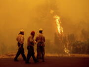 Flames from the McKinney Fire burn beyond firefighters in Klamath National Forest, Calif., on Sunday, July 31, 2022.