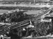 This 1953 photograph shows Jantzen Beach Amusement Park, along with its swimming pool and roller coaster, as well as the single-spanned Interstate 5 Bridge across the Columbia River.