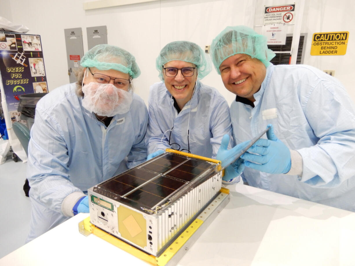 Wesley Faler, Don Smith and Alex Wingeier with the miniature satellite known as a CubeSat that they built. It aboard NASA's Artemis 1 when it lifted off on Saturday and will propel itself into deep space.