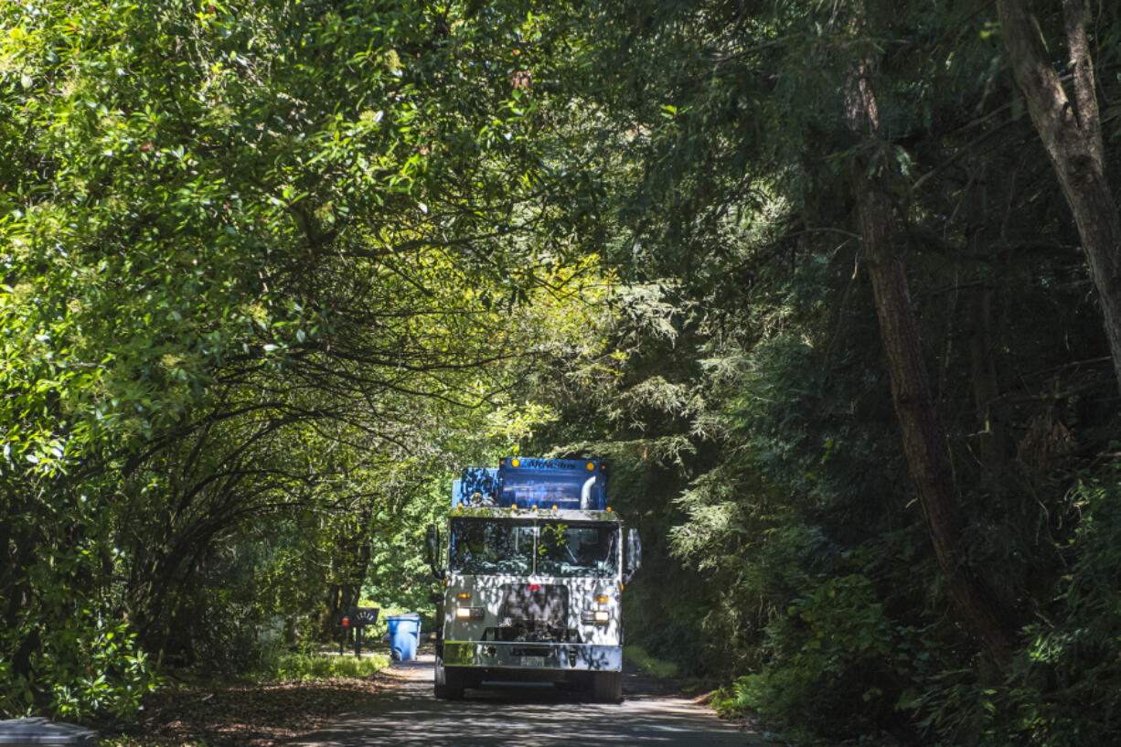 Gabe Durate, a residential garbage truck driver with Waste Connections, collects garbage in an east Vancouver neighborhood in 2019.