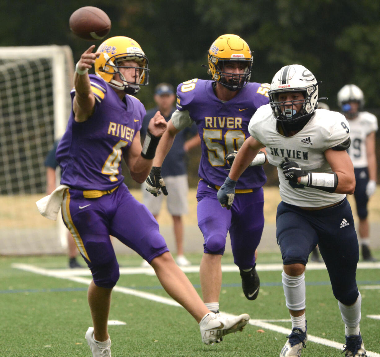 Columbia River quarterback Adam Watts, left, zips a pass on the run while being chased by Skyview’s Gavin Poffenroth, right, on Saturday at Kiggins Bowl in Vancouver.