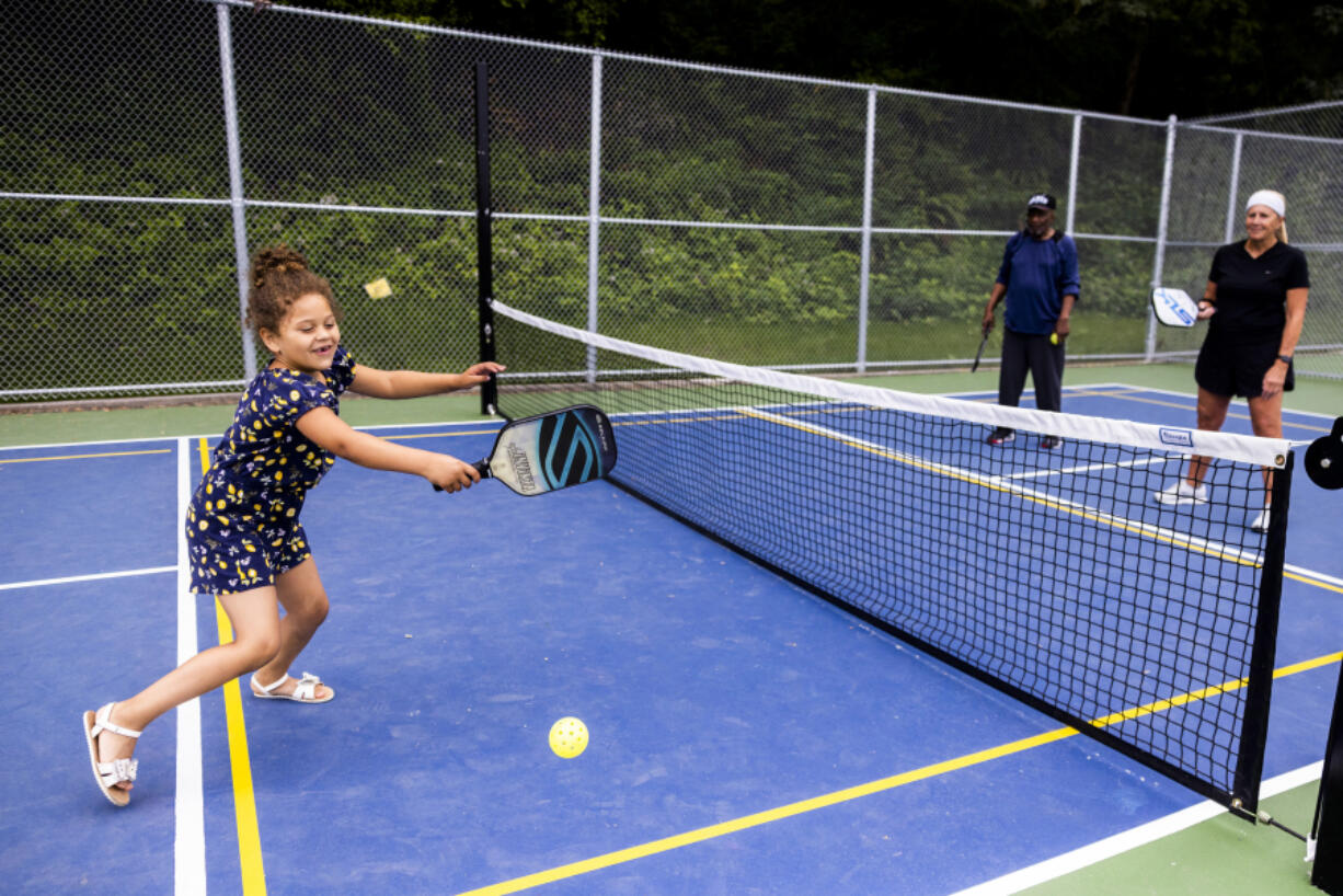 Amara Erickson, 5, left, smiles as she plays her first game of pickleball July 2 at Lakeridge Playfield in Seattle. Pickleball is the official sport of the state of Washington. The game was invented on Bainbridge Island in 1965.