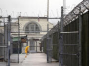 In this Jan. 28, 2016, file photo, a man does maintenance work between razor wire-topped fences at the Monroe Correctional Complex in Monroe.