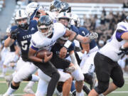 Skyview defenders Ty Evans, left, Kellen Wiggins, top right, and Cameron Crooks, bottom right, combine to make a tackle on Kamiak quarterback Ben'tre Worthy on Friday at Kiggins Bowl in Vancouver.