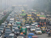 Commuters make their way along a busy road under heavy smoggy conditions in New Delhi on November 12, 2021.