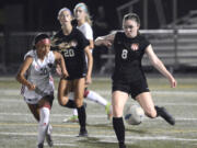 Nora Melcher, right, of Camas flips a pass ahead to a teammate while being defended by Union's Ohu Miles on Tuesday at Doc Harris Stadium in Camas.