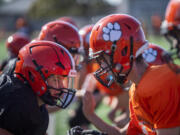 Battle Ground football players practice Tuesday, Sept. 20, 2022, at Battle Ground High School. Ex-NFL player Michael Roos purchased custom-made Axiom helmets, shown at left, for a number of Tigers to wear. The helmets are designed for each player's specific head and include impact sensing and other technology for better safety.