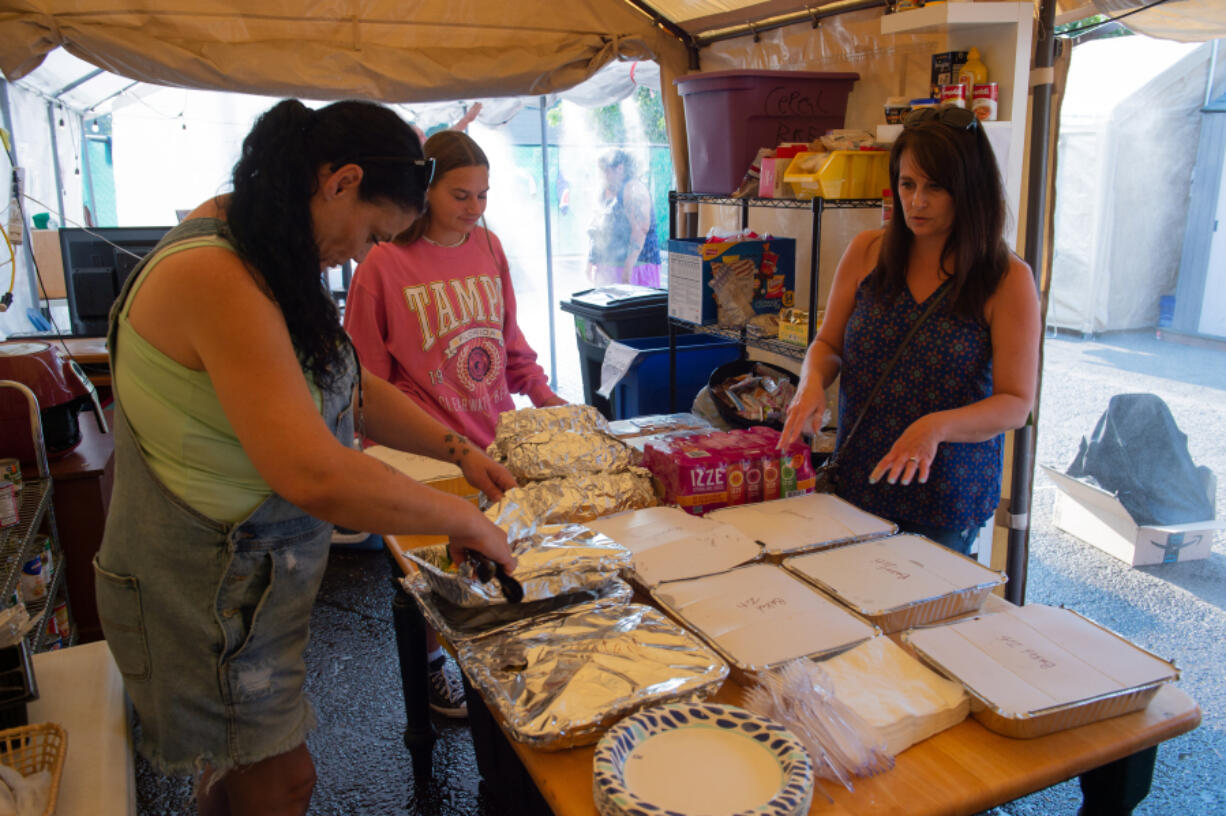 Michelle Sanow, right, and her daughter, Amelia Picinich, center, brought dinner to the Safe Stay Community in Vancouver's North Image neighborhood Wednesday evening, with Outsiders Inn Shelter Peer Worker Crystal Drake, left. Sanow spent half the day preparing baked ziti, salad and steamed broccoli for the Safe Stay residents.