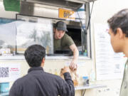 Little Conejo Norte employee Jacob Brill hands a bag of chips to a customer at Carts by the Park in Ridgefield.