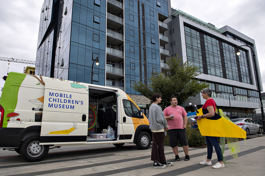 Megan Whetsell, left, and Erek Watson, both of Vancouver, chat with Jeanne Bennett of Columbia Play Project, dressed as "Doug the Slug," as she hands out flyers during Give More24! at The Waterfront Vancouver in September.