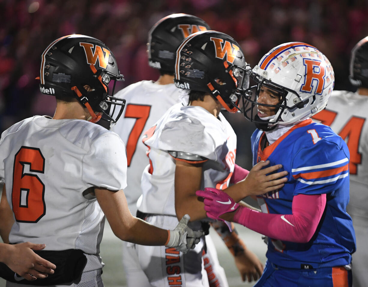 Ridgefield senior Isaiah Cowley, right, congratulates Washougal players on a good game Friday, Sept. 30, 2022, after the Spudders’ 34-27 loss to Washougal at Ridgefield High School.