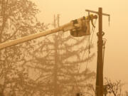 FILE - Workers continue to repair the power system after flames from the Beachie Creek Fire burned through Fishermen's Bend Recreation in Mill City, Ore., on Sept. 13, 2020. Oregon utilities began shutting down power to thousands of customers on Friday, Sept. 9, 2022, as dry easterly winds swept into the region, raising the risk of wildfire danger. Portland General Electric halted power in the Columbia River Gorge and around Mount Hood and a second power company was poised to do the same Friday.