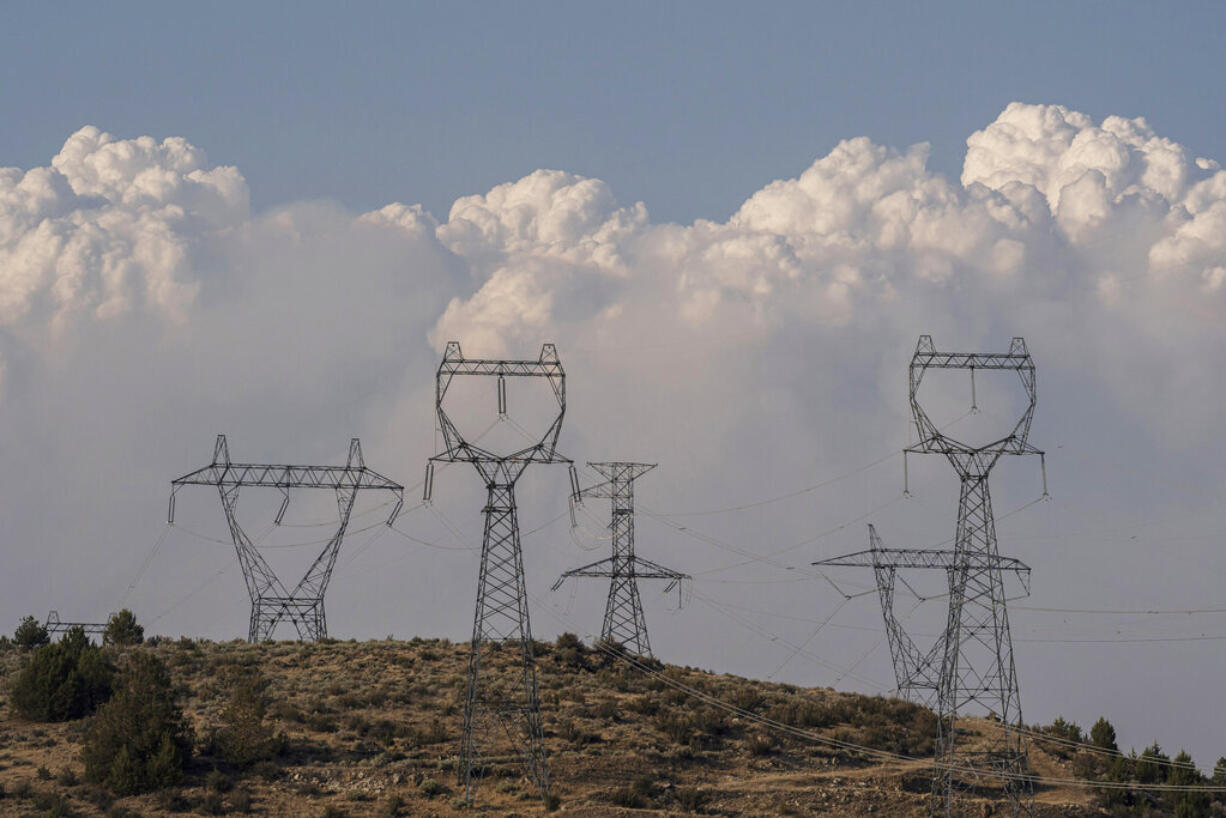 FILE - Smoke plumes from the Bootleg Fire rise over power lines on July 12, 2021, near Klamath Falls, Ore. Oregon utilities began shutting down power to thousands of customers on Friday, Sept. 9, 2022, as dry easterly winds swept into the region, raising the risk of wildfire danger. Portland General Electric halted power in the Columbia River Gorge and around Mount Hood and a second power company was poised to do the same Friday.