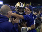 Fans celebrate with Washington quarterback Michael Penix Jr., center, after an NCAA college football game against Michigan State, Saturday, Sept. 17, 2022, in Seattle.