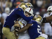 Washington's Zion Tupuola-Fetui, left, and Cam Bright, right, sack Stanford quarterback Tanner McKee during the first half of an NCAA college football game Saturday, Sept. 24, 2022, in Seattle.