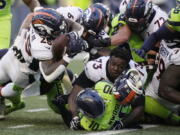 Denver Broncos running back Melvin Gordon III, upper left, fumbles the ball as Broncos offensive tackle Cameron Fleming (73) loses his helmet during the second half of an NFL football game against the Seattle Seahawks, Monday, Sept. 12, 2022, in Seattle.