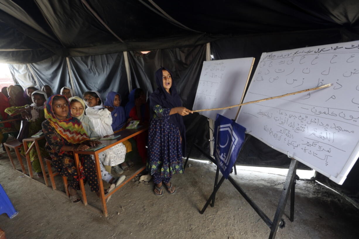 Flood affected children attend school organized by Islamic group Jamaat-e-Islami Pakistan, in Sukkur, Pakistan, Sunday, Sept. 4, 2022. Officials warned Sunday that more flooding was expected as Lake Manchar in southern Pakistan swelled from monsoon rains that began in mid-June and have killed nearly 1,300 people.