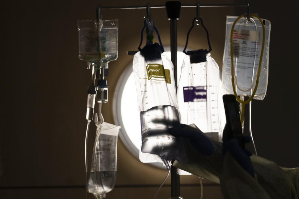 FILE - A nurse checks on IV fluids while talking to a COVID-19 patient at Providence Holy Cross Medical Center in Los Angeles, Dec. 13, 2021. A majority of adults in the U.S. say health care is not handled well in the country. That's according to a new poll from The Associated Press-NORC Center for Public Affairs Research. (AP Photo/Jae C.