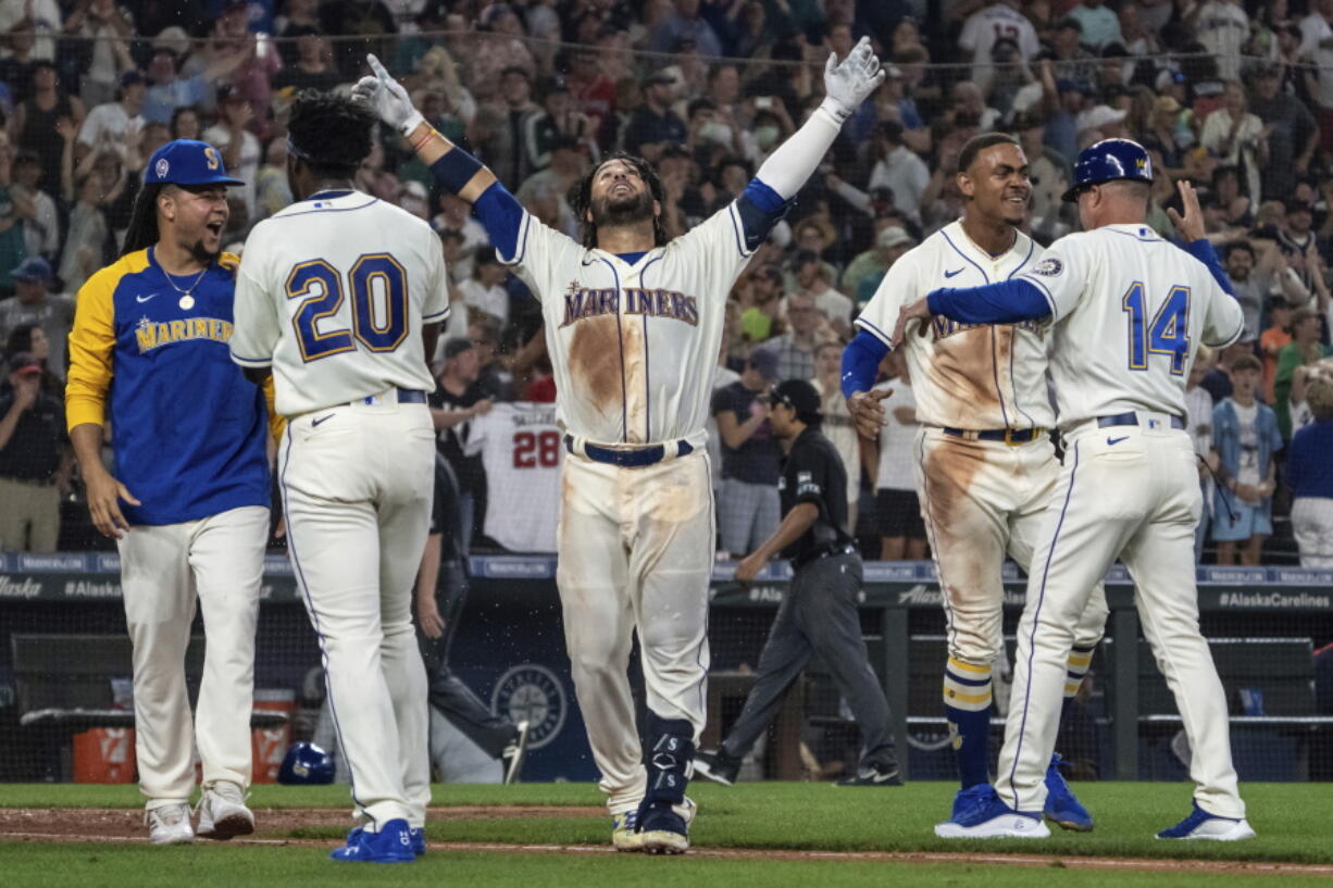 Seattle Mariners' Eugenio Suarez, center, celebrates with Luis Castillo, left, Taylor Trammell (20), Julio Rodriguez, second from right, and third base coach Manny Acta, right, after hitting a walkoff solo home run after a baseball game against the Atlanta Braves, Sunday, Sept. 11, 2022, in Seattle.