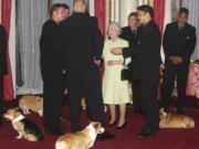 FILE - Britain's Queen Elizabeth II meets the New Zealand All Blacks rugby team will the royal corgis in attendance at Buckingham Palace, London Tuesday Nov. 5, 2002. Queen Elizabeth II's corgis were a key part of her public persona and her death has raised concern over who will care for her beloved dogs. The corgis were always by her side and lived a life of privilege fit for a royal. She owned nearly 30 throughout her life. She is reportedly survived by four dogs.