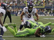 Denver Broncos quarterback Russell Wilson (3) watches as Seattle Seahawks cornerback Mike Jackson, front, recovered the football after it was fumbled by Broncos running back Javonte Williams during the second half of an NFL football game, Monday, Sept. 12, 2022, in Seattle.