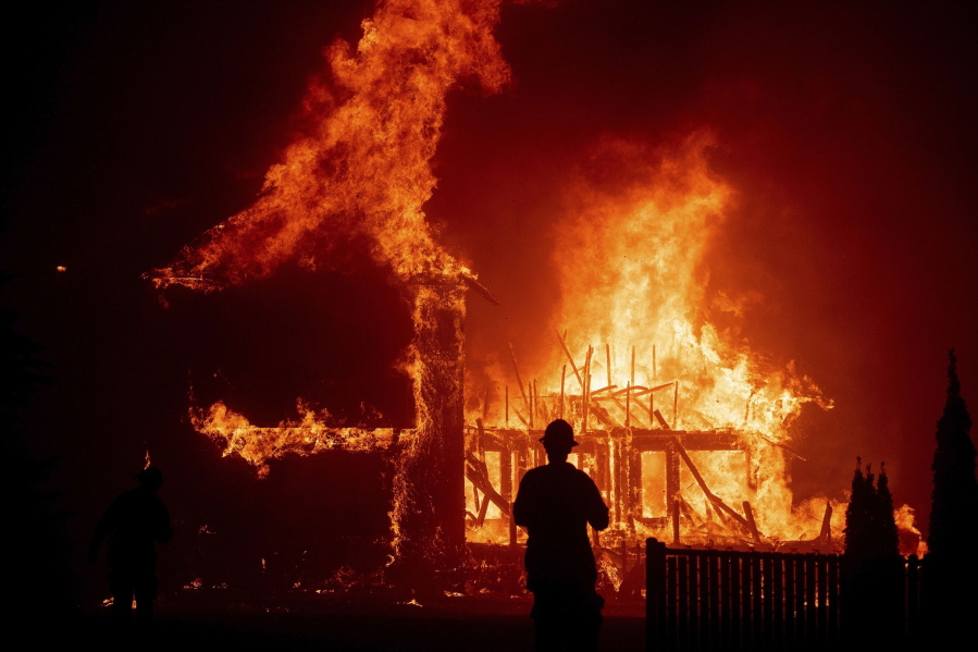 FILE - A home burns as the Camp Fire rages through Paradise, Calif., Nov. 8, 2018. Former executives and directors of Pacific Gas & Electric have agreed to pay $117 million to settle a lawsuit over devastating 2017 and 2018 California wildfires sparked by the utility's equipment, it was announced Thursday, Sept. 29, 2022.