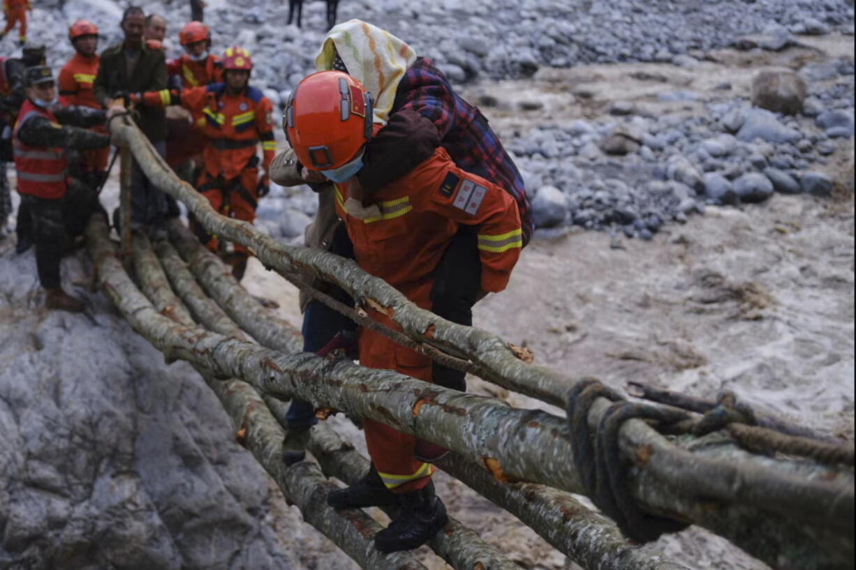 In this photo released by Xinhua News Agency, rescuers carry a villager across a river following an earthquake in Moxi Town of Luding County, southwest China's Sichuan Province on Monday, Sept. 5, 2022. Dozens people were reported killed and missing in a 6.8 magnitude earthquake that shook China's southwestern province of Sichuan on Monday, triggering landslides and shaking buildings in the provincial capital of Chengdu, whose 21 million residents are already under a COVID-19 lockdown.