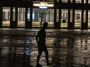 A man walks through a flooded street in front of a hotel powered by an oil generator during a blackout in Havana, Cuba, Wednesday, Sept. 28, 2022. Cuba remained in the dark early Wednesday after Hurricane Ian knocked out its power grid and devastated some of the country's most important tobacco farms when it hit the island's western tip as a major storm.