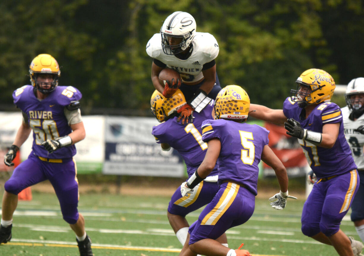 Skyview running back Trey Jacob (3) attempts to hurdle over Columbia River defender Joseph Pena (1) on Saturday at Kiggins Bowl in Vancouver.