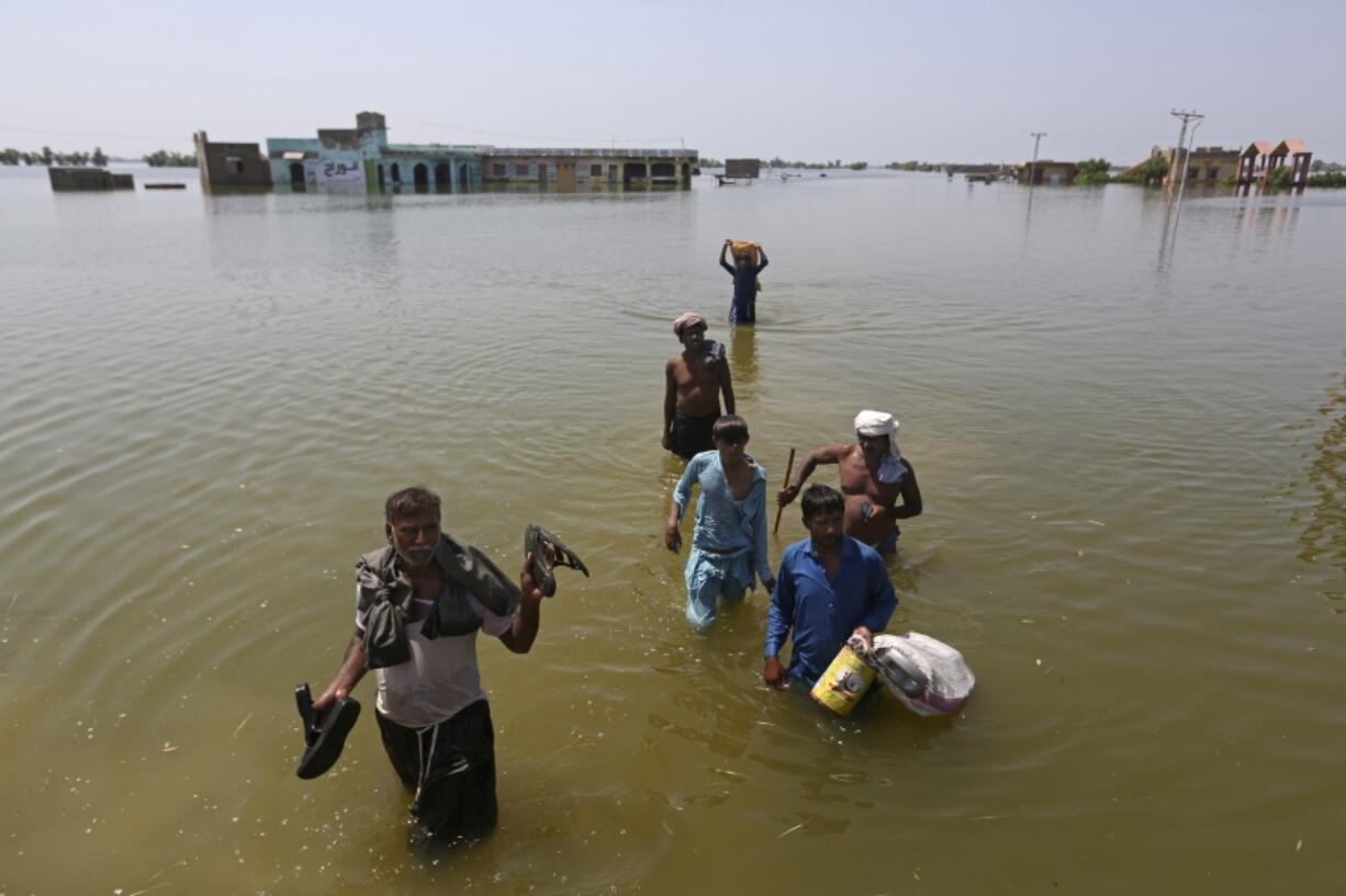 FILE - Victims of flooding from monsoon rains carry belongings salvaged from their flooded home in the Dadu district of Sindh Province, of Pakistan, Sept. 9, 2022. Ten years ago scientists warned the world about how climate change would amplify extreme weather disasters. There are now deadly floods, oppressive heat waves, killer storms, devastating droughts and what scientists call unprecedented extremes as predicted in 2012.