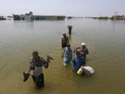 FILE - Victims of flooding from monsoon rains carry belongings salvaged from their flooded home in the Dadu district of Sindh Province, of Pakistan, Sept. 9, 2022. Ten years ago scientists warned the world about how climate change would amplify extreme weather disasters. There are now deadly floods, oppressive heat waves, killer storms, devastating droughts and what scientists call unprecedented extremes as predicted in 2012.