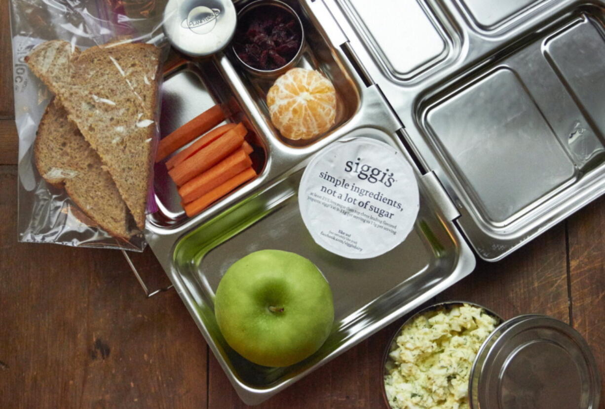 A vegetarian boxed school lunch with carrot sticks and fruit.