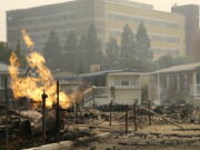 FILE - With Kaiser Permanente's Santa Rosa Medical Center in the background, a flame from an open gas valve burns at the Journey's End mobile home park on Oct. 9, 2017, in Santa Rosa, Calif. Dr. Suzy Fitzgerald helped with the evacuation of 122 patients from Kaiser Permanente's Santa Rosa Medical Center nearly five years ago, as the blaze gobbled up homes and buildings across Northern California. The hospital, which had filled with smoke, closed for 17 days.