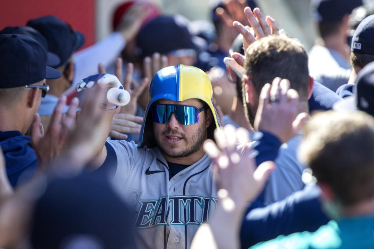 Seattle Mariners' Ty France is congratulated by teammates after hitting a three-run home run against the Los Angeles Angels during the seventh inning of a baseball game in Anaheim, Calif., Monday, Sept. 19, 2022.