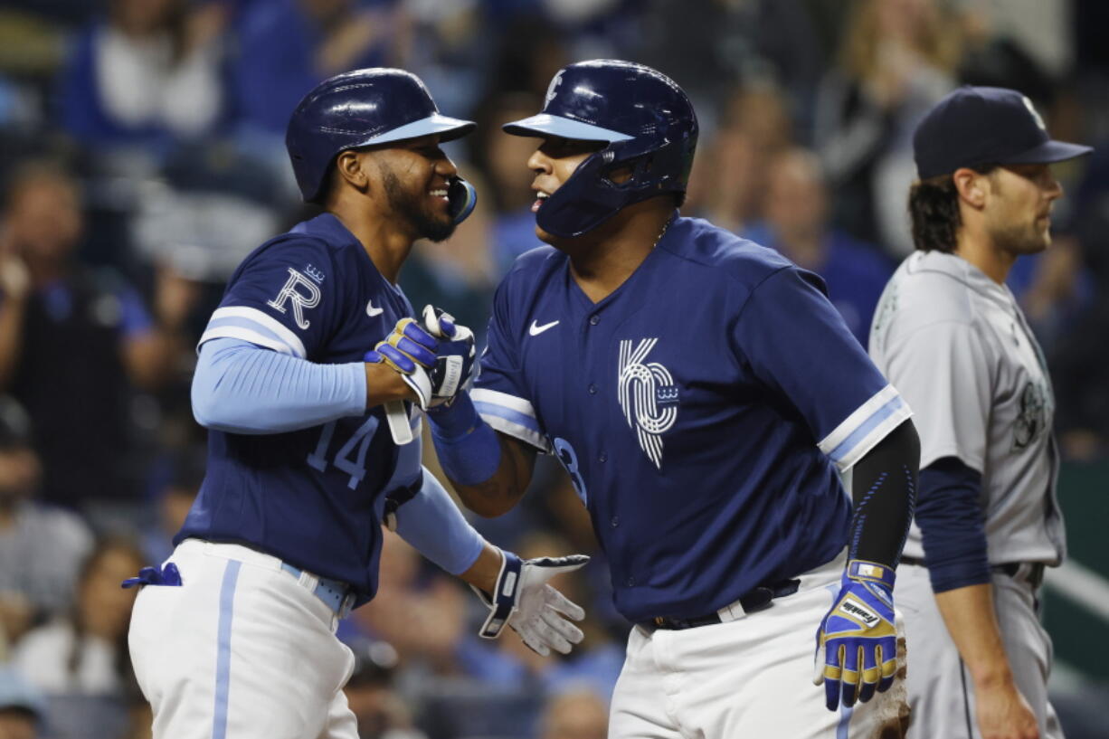 Kansas City Royals' Edward Olivares (14) congratulates Salvador Perez, right, after Perez scored from second off a Vinnie Pasquantino single during the seventh inning of a baseball game against the Seattle Mariners in Kansas City, Mo., Friday, Sept. 23, 2022. (AP Photo/Colin E.