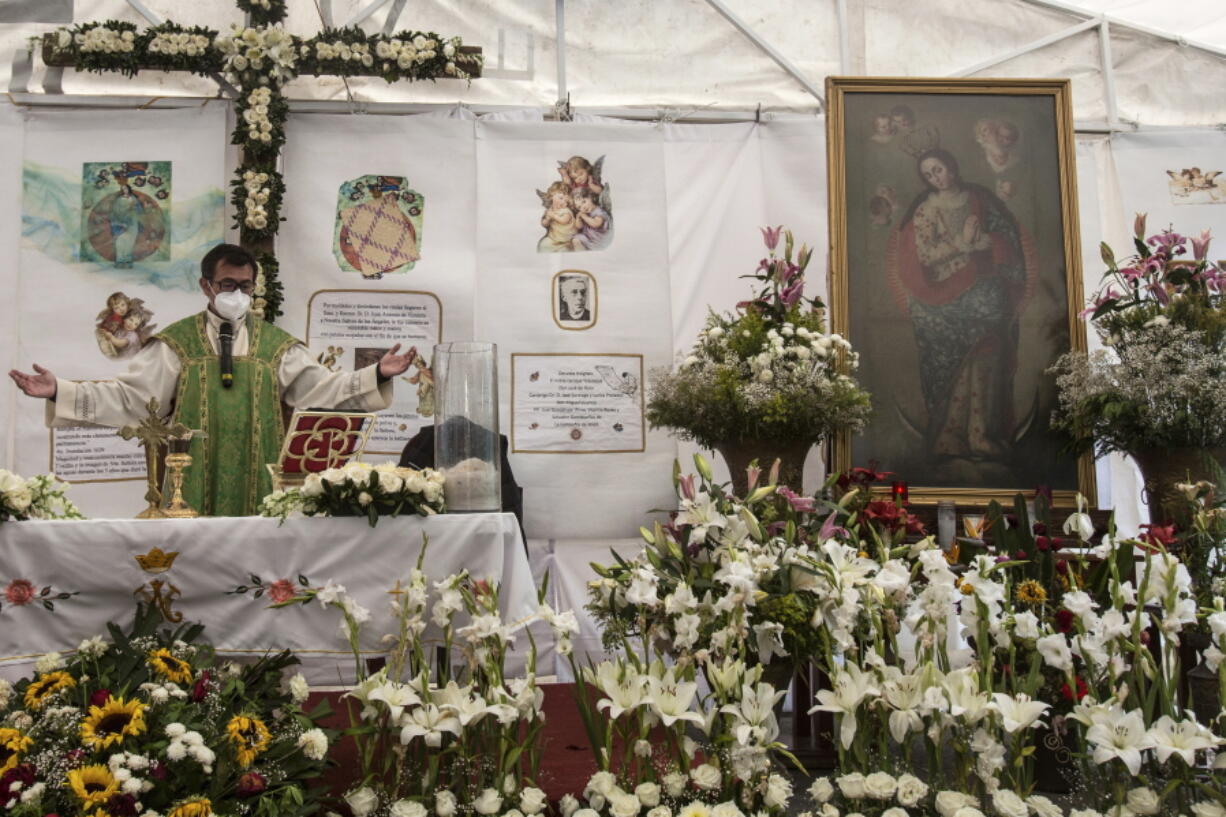 Rev. Adrian Vazquez celebrates an outdoor Mass under a white tent outside the quake-damaged Our Lady of the Angels church, in the working-class Guerrero neighborhood of Mexico City, Sunday, Aug. 7, 2022. Pictured right is a wax painting of Our Lady of the Angels, a replica of the one on the wall inside the church, home to the revered image of the Virgin Mary, its history dating to the end of the 16th century.