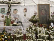 Rev. Adrian Vazquez celebrates an outdoor Mass under a white tent outside the quake-damaged Our Lady of the Angels church, in the working-class Guerrero neighborhood of Mexico City, Sunday, Aug. 7, 2022. Pictured right is a wax painting of Our Lady of the Angels, a replica of the one on the wall inside the church, home to the revered image of the Virgin Mary, its history dating to the end of the 16th century.