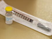 FILE - A vial containing the monkeypox vaccine and a syringe is set on the table at a vaccination clinic run by the Mecklenburg County Public Health Department in Charlotte, N.C., Saturday, Aug. 20, 2022. At-risk people who received just one dose of the monkeypox vaccine appeared to be significantly less likely to get sick from the virus, public health officials announced Wednesday, even as they urged a second dose for full protection.