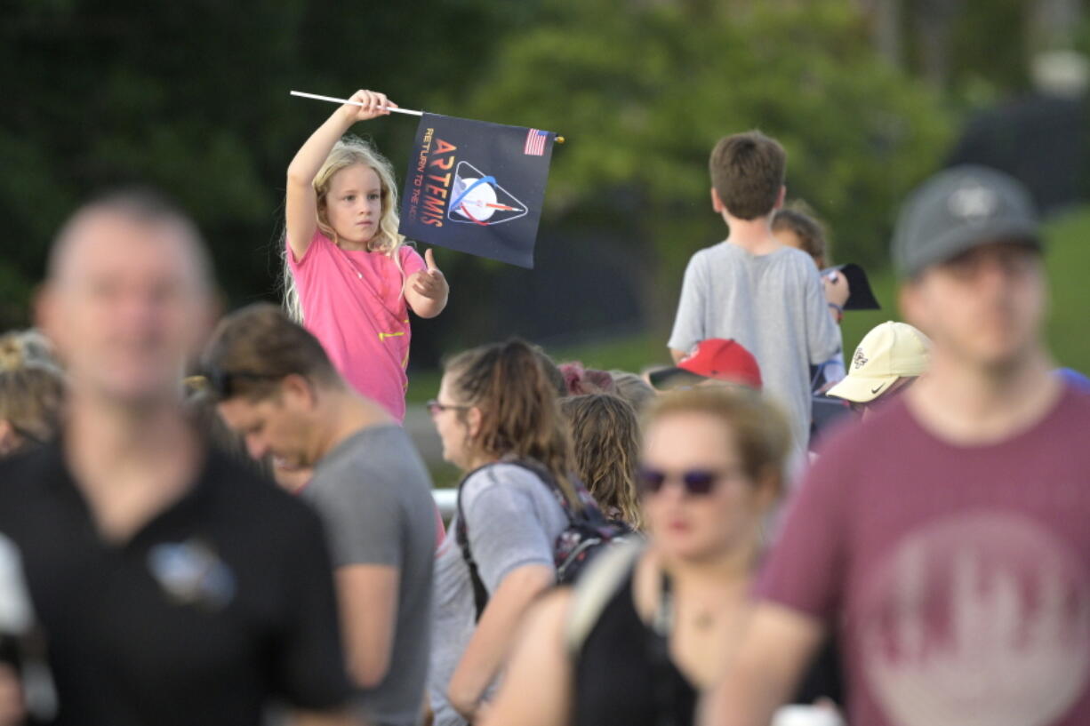 A child waves a souvenir flag while waiting on the Max Brewer Bridge to view the launch on Pad 39B for the Artemis I mission to orbit the moon at the Kennedy Space Center, Monday, Aug. 29, 2022, in Titusville, Fla. The launch was scrubbed. (AP Photo/Phelan M.