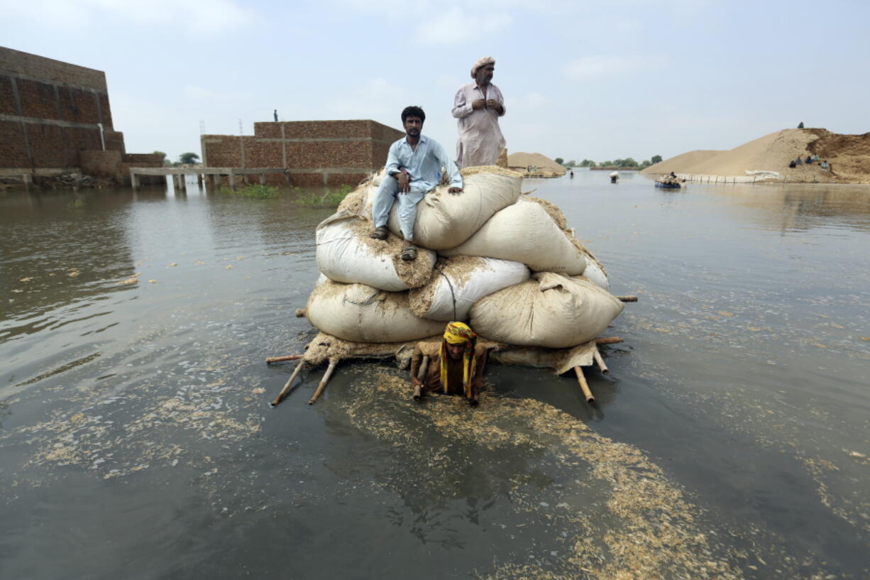 Victims of the unprecedented flooding from monsoon rains use makeshift barge to carry hay for cattle, in Jaffarabad, a district of Pakistan's southwestern Baluchistan province, Monday, Sept. 5, 2022. The U.N. refugee agency rushed in more desperately needed aid Monday to flood-stricken Pakistan as the nation's prime minister traveled to the south where rising waters of Lake Manchar pose a new threat.