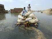 Victims of the unprecedented flooding from monsoon rains use makeshift barge to carry hay for cattle, in Jaffarabad, a district of Pakistan's southwestern Baluchistan province, Monday, Sept. 5, 2022. The U.N. refugee agency rushed in more desperately needed aid Monday to flood-stricken Pakistan as the nation's prime minister traveled to the south where rising waters of Lake Manchar pose a new threat.