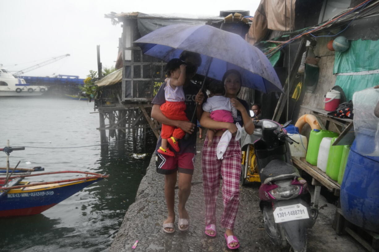 Residents carry their children as they evacuate to safer grounds to prepare for the coming of Typhoon Noru at the seaside slum district of Tondo in Manila, Philippines, Sunday, Sept. 25, 2022. The powerful typhoon shifted and abruptly gained strength in an "explosive intensification" Sunday as it blew closer to the northeastern Philippines, prompting evacuations from high-risk villages and even the capital, which could be sideswiped by the storm, officials said.