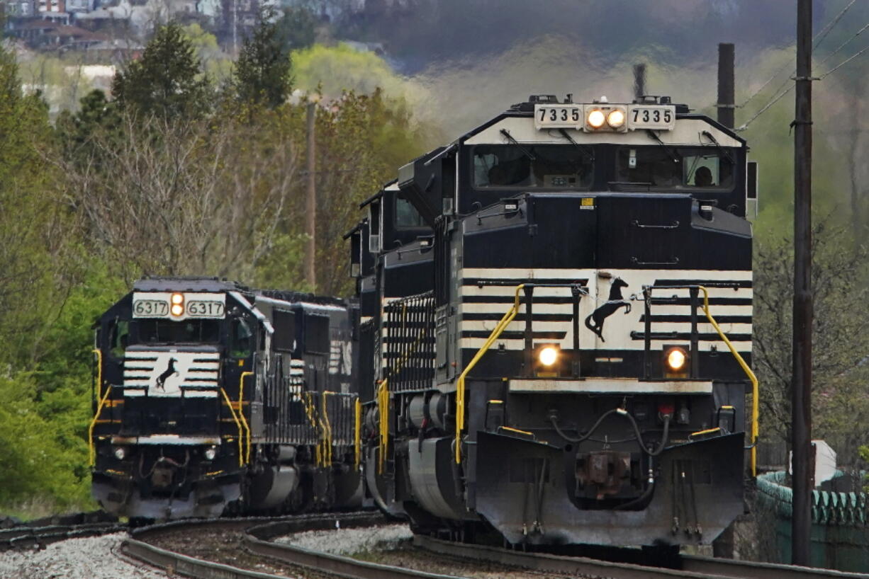 A Norfolk Southern freight train passes a train on a siding as it approaches a crossing in Homestead, Pa., on April 27.