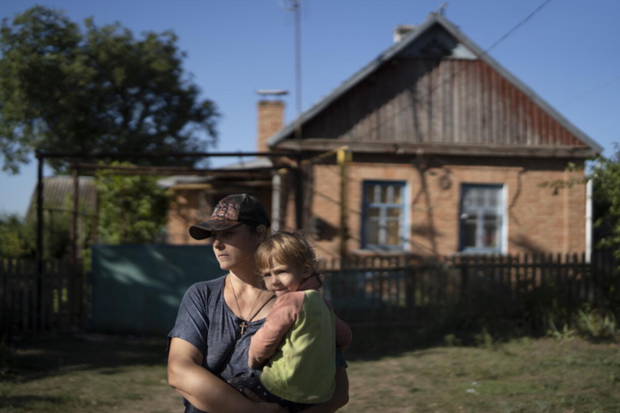 Natalia Stokoz holds her daughter, Veronika, 3, in front of their house in the village of Zorya, about 12 miles from the Zaporizhzhia nuclear power plant. Stokoz, a single mother of three, said it's not the shelling that scares her most; it's the risk of a radiation leak from the plant.