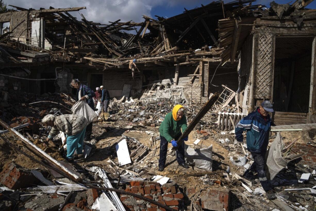 Local residents collect wood for heating from a destroyed school where Russian forces were based, in the recently retaken area of Izium, Ukraine, Monday, Sept. 19, 2022. Residents of Izium, a city recaptured in a recent Ukrainian counteroffensive that swept through the Kharkiv region, are emerging from the confusion and trauma of six months of Russian occupation, the brutality of which gained worldwide attention last week after the discovery of one of the world's largest mass grave sites.