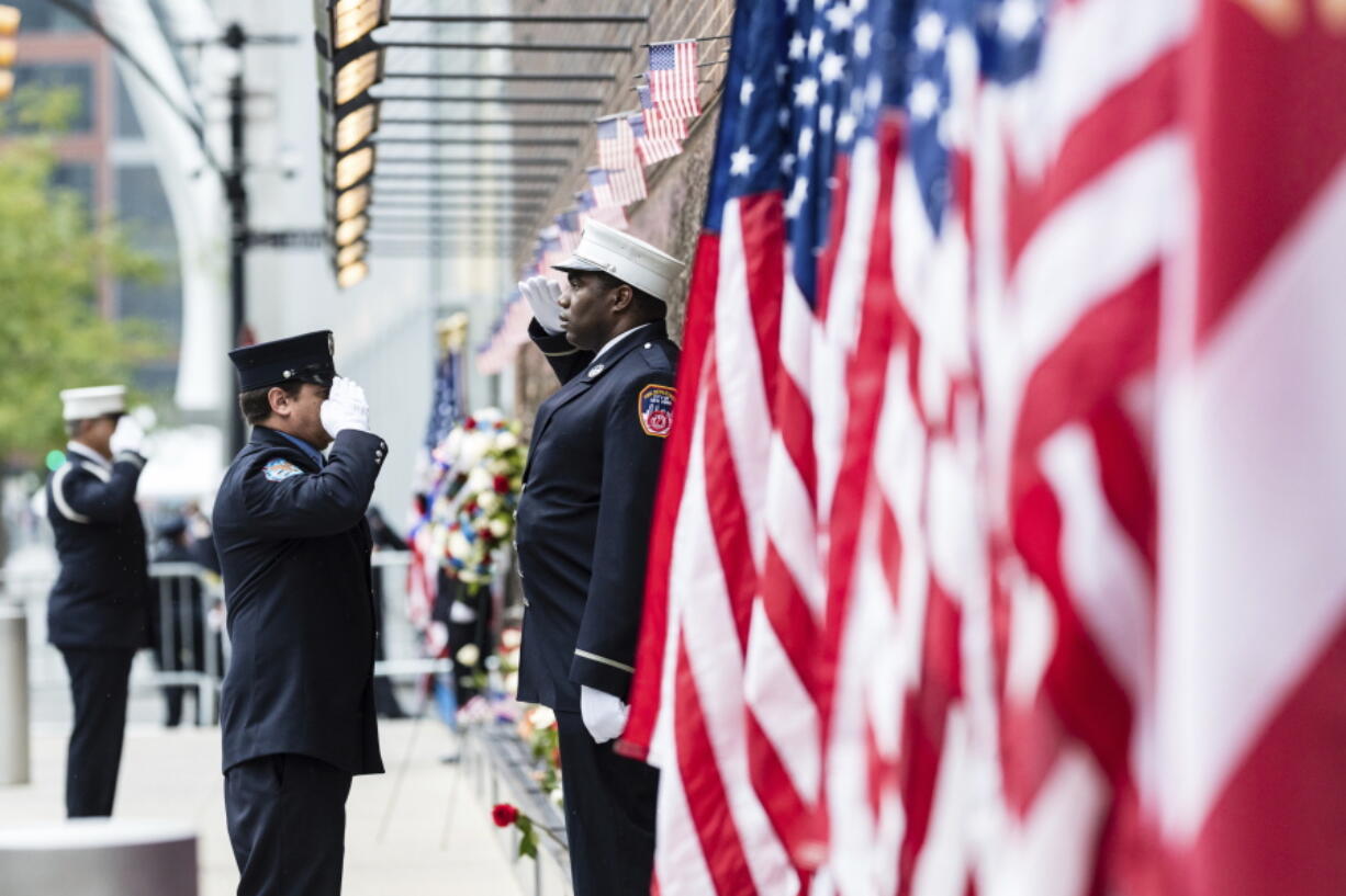 Firefighters salute each other outside the FDNY Engine 10, Ladder 10 fire station near the commemoration ceremony on the 21st anniversary of the September 11, 2001 terror attacks on Sunday, Sept. 11, 2022 in New York.