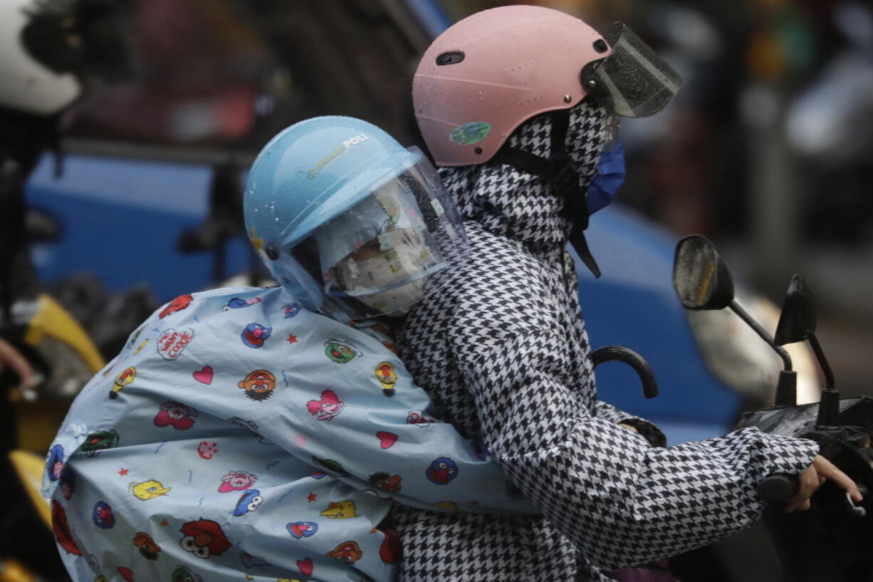 People ride scooter in the rain ahead of the approaching Typhoon Muifa in Taipei, Taiwan, Monday, Sept. 12, 2022.