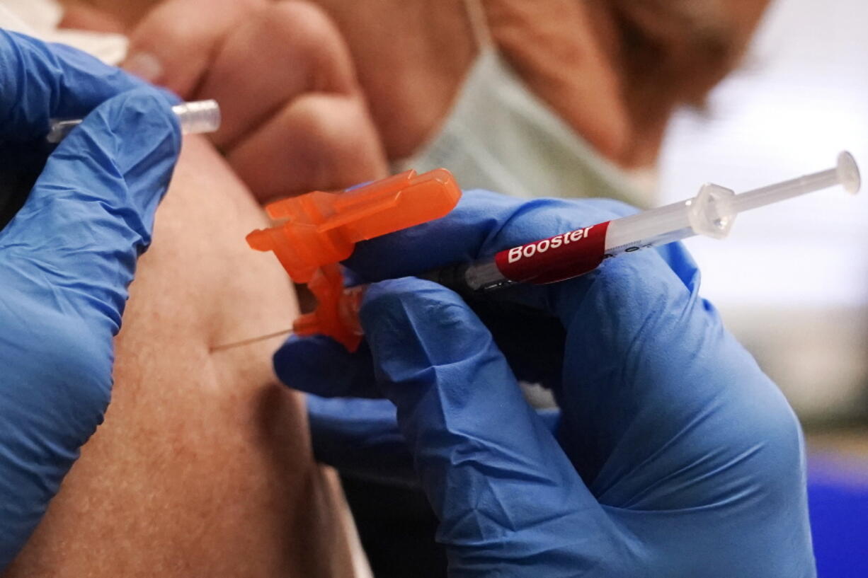 FILE - A pharmacist injects a patient with a booster dosage of the Moderna COVID-19 vaccine at a vaccination clinic in Lawrence, Mass., on Wednesday, Dec. 29, 2021.  U.S. regulators have authorized updated COVID-19 boosters, the first to directly target today's most common omicron strain. The move on Wednesday, Aug. 13, 2022,  by the Food and Drug Administration tweaks the recipe of shots made by Pfizer and rival Moderna  that already have saved millions of lives.